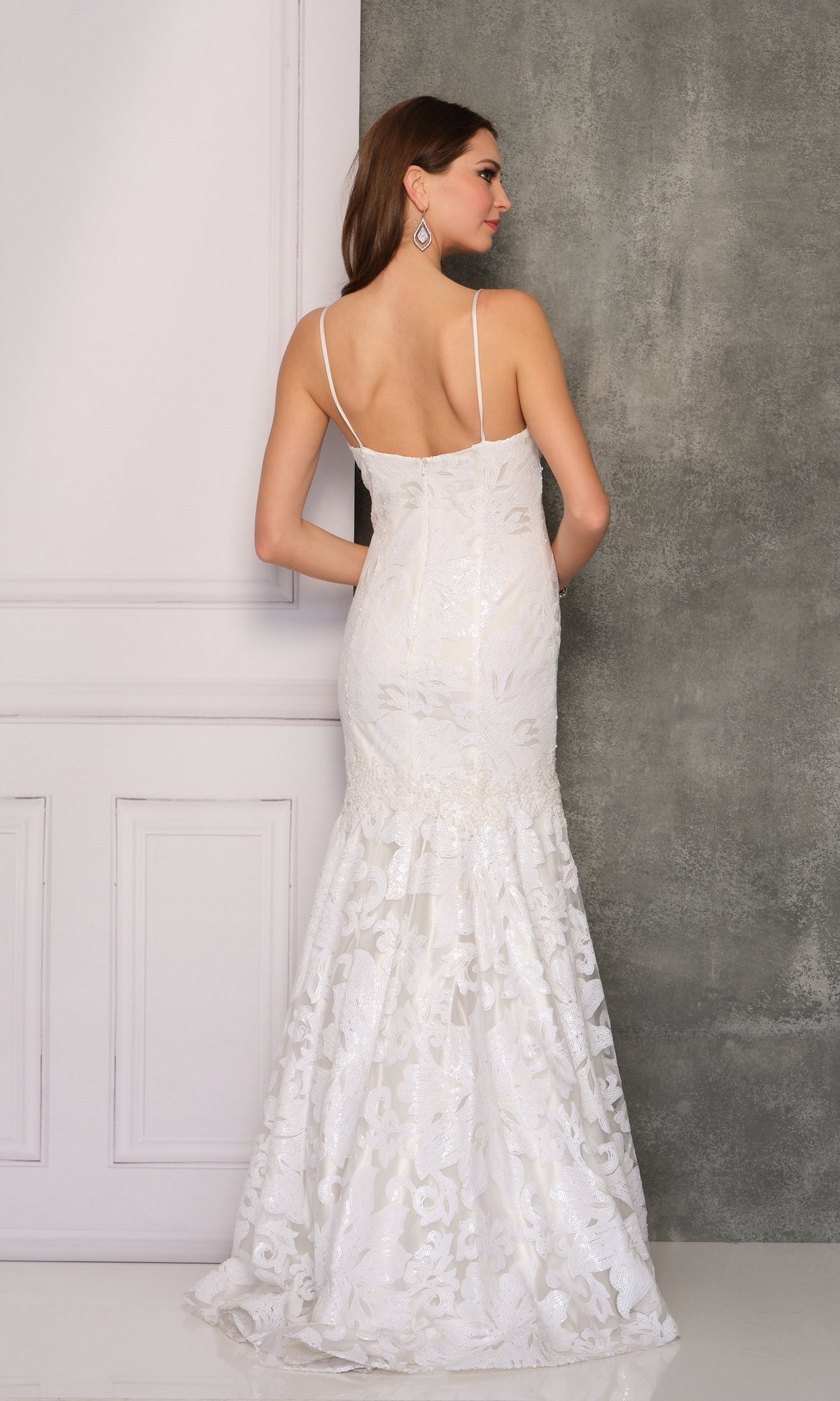 A woman stands with her back to the camera against a gray and white background, wearing the Long Formal Dress A6768 by Dave and Johnny—a white, fitted mermaid gown with a sweetheart neckline and lace floral details.